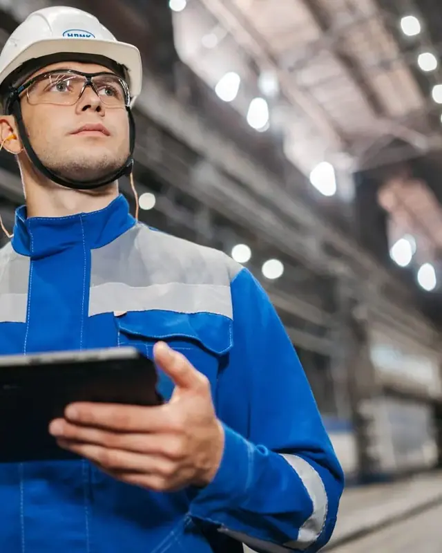 HSE engineer with a hard hat and a tablet in a large industrial hall