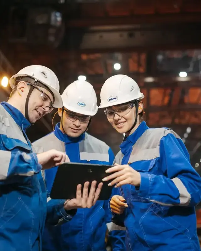 Trois techniciens HSE consultant une tablette dans un atelier industriel