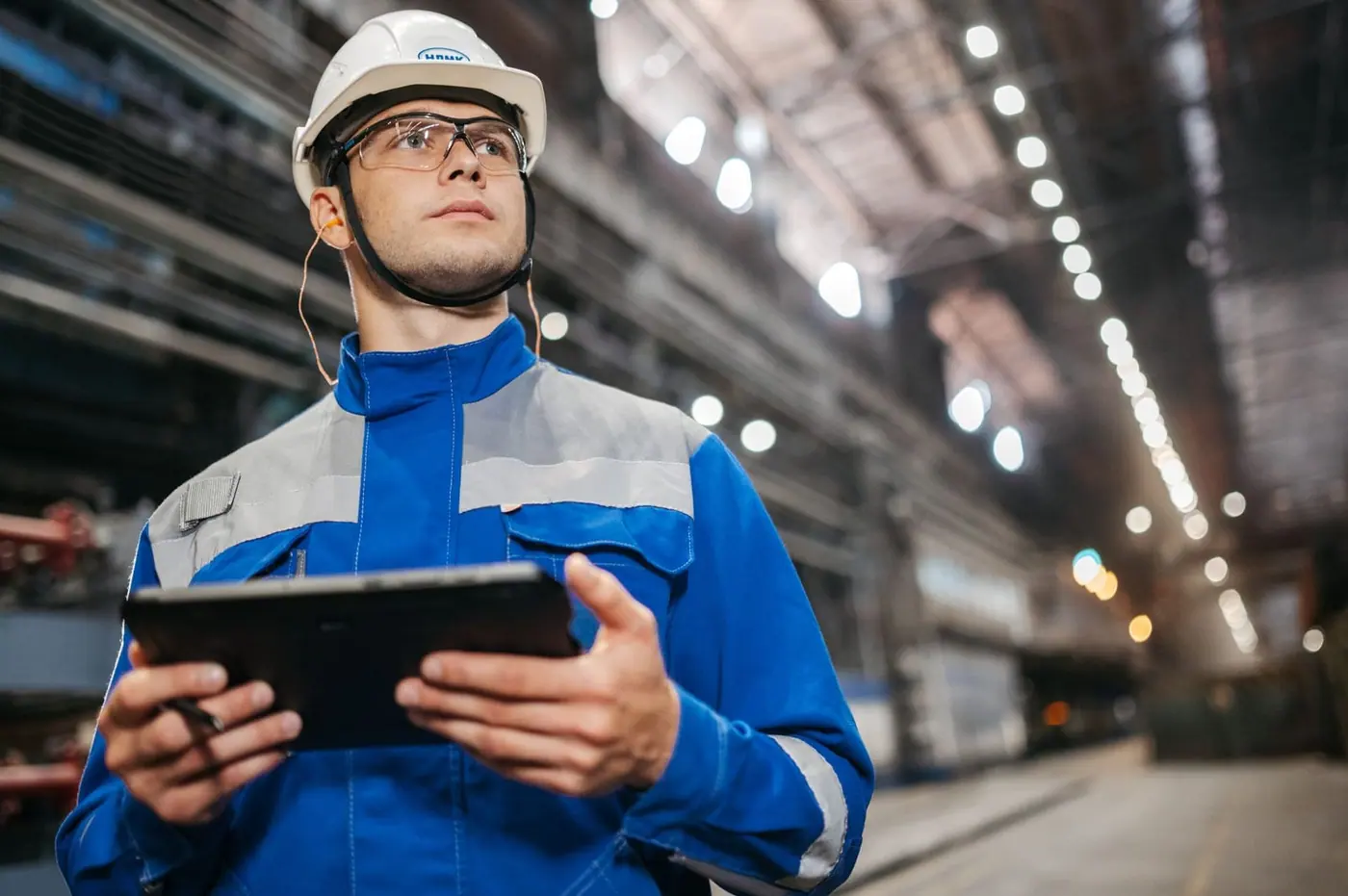 Ingénieur HSE avec une tablette dans une halle industrielle